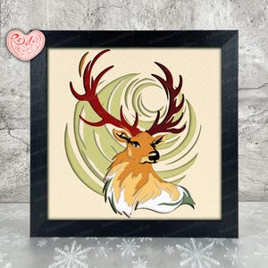 May include: Framed art print featuring a stylized deer with large, reddish-brown antlers. The deer is rendered in shades of orange, yellow, and white, set against a light green spiral design. The artwork is framed in a black square frame.
