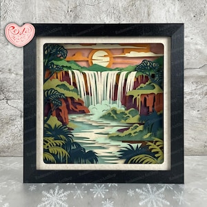 Peut inclure: Une œuvre d'art encadrée en papier représentant une scène de cascade. L'œuvre utilise des couches de papier découpé pour créer de la profondeur, avec une cascade se jetant dans une rivière. La palette de couleurs comprend des verts, des oranges et des bleus, avec un cadre noir. L'œuvre est signée "Redamancy ArtShop".