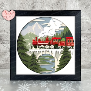 以下が含まれることがあります： 雪景色の中、雪の橋を渡る赤い列車を描いた、額入りのペーパーアート作品。アートワークには山、木、青い空が含まれています。フレームは黒で、アートワークは円形です。「Redamancy ArtShop」の文字が見えます。