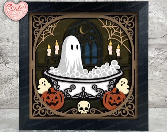 May include: A layered paper shadow box art piece in a black frame featuring a white ghost sitting in a bathtub filled with bubbles. The scene includes orange jack-o'-lanterns, a skull, lit candles, and a crescent moon against a dark background.