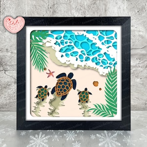 May include: A framed paper art piece showing a beach scene with three turtles heading towards the sea. The artwork uses layers of paper in blue, green, beige, and white, creating a 3D effect. A starfish and seashells are also included.