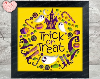 May include: A black framed picture with a yellow background and a paper cut-out design of a ghost, a witch's hat, candy canes, and a house. The text "Trick or Treat" is in the center of the design.