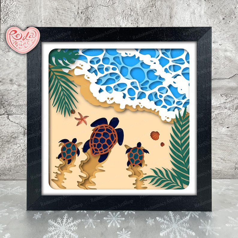 May include: A framed paper art piece showing a beach scene with three turtles, ocean waves, and palm fronds. The turtles are dark blue with patterned shells, and the waves are layered blue and white. The frame is black.