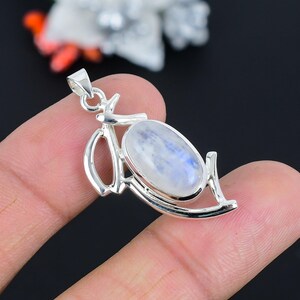Op de afbeelding: Een zilveren hanger met een ovale maansteen cabochon. De hanger is in een delicaat, abstract ontwerp met een zilveren lus.
