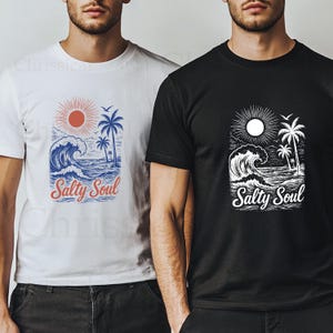 May include: Two t-shirts with a graphic design of a wave, palm trees, and a sun. The text "Salty Soul" is printed on both shirts. One shirt is white with a red sun and the other shirt is black with a white sun.