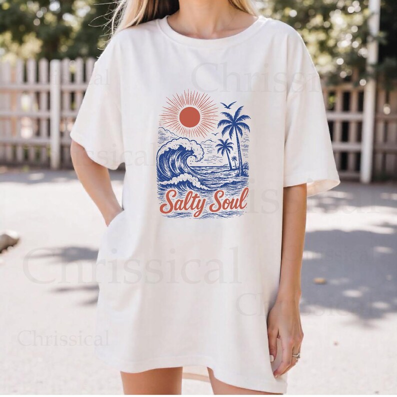 May include: White oversized t-shirt with a graphic of a blue wave, palm trees, and a red sun. The text "Salty Soul" is printed in red and blue below the graphic.