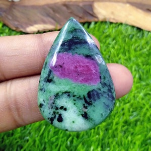 May include: A teardrop-shaped green and pink gemstone cabochon with a polished finish. The stone has a green and black base with a pink band across the centre.