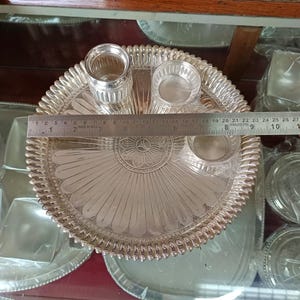 May include: A silver serving tray with a decorative floral design and three small bowls. The tray is 8 inches in diameter.