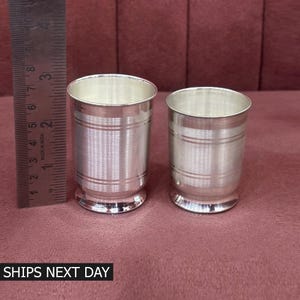 Peut inclure: Une tasse en céramique blanche avec une anse noire et le texte "But First, Coffee" en gras noir. La tasse est posée sur une surface blanche, mettant en valeur son design épuré.