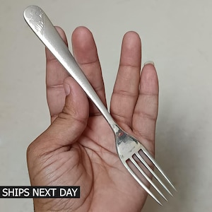 May include: A silver fork with a decorative design on the handle. The fork has four tines and is held in a hand. The text "SHIPS NEXT DAY" is at the bottom of the image.