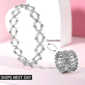 Puede incluir: Un anillo de plata que se puede convertir en una pulsera. El anillo está hecho de eslabones de metal entrelazados con pequeñas piedras transparentes. El texto "Convertible" está escrito en la imagen.