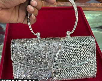 May include: A silver-colored handbag with intricate floral and lattice patterns. The bag features a curved handle and a decorative clasp. The text "SHIPS NEXT DAY" is visible at the bottom of the image.
