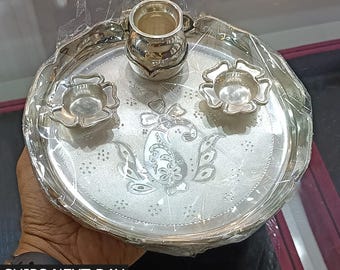 Può includere: Un vassoio rotondo in argento con un designo decorativo e tre piccole ciotole in argento. Il vassoio è rotondo e ha un bordo rialzato. Le ciotole sono tutte della stessa dimensione e hanno un design floreale.