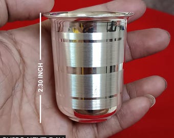 Puede incluir: Un vaso de beber de plata con un diseño a rayas. El vaso mide 2,30 pulgadas de alto.