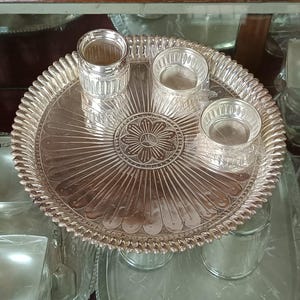 May include: A silver serving tray with a decorative floral design in the center. The tray is surrounded by four smaller silver bowls.