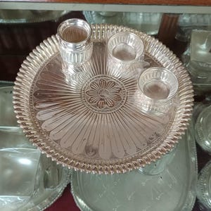 May include: A silver serving tray with a decorative floral design in the center. The tray is surrounded by three small silver bowls.