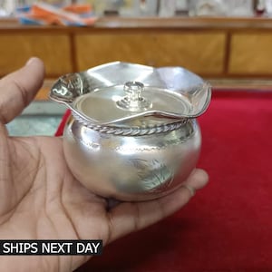 May include: A silver container with a lid, featuring a leaf design. The container has a fluted edge and a rope-like design around the top.