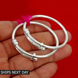 May include: Two silver bangles with a beaded design. The bangles are stacked on top of each other.