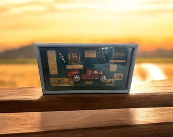 Peut inclure: Un présentoir encadré gris avec une voiture de course rouge vintage, portant le numéro 8. Il comprend des illustrations d'époque et une bougie d'allumage. Le cadre est posé sur une surface en bois, avec un arrière-plan extérieur flou.
