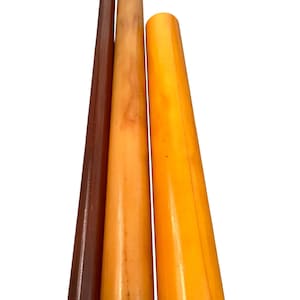 Puede incluir: Tres candeleros de madera en diferentes tonos de marrón y amarillo. Los candeleros son cónicos, con una base más ancha y una parte superior más estrecha. Los colores varían del marrón oscuro al amarillo claro.