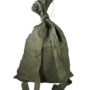 Op de afbeelding: Olijfgroene rugzak van canvas met verstelbare schouderbanden. De tas heeft een trekkoordsluiting aan de bovenkant. De banden zijn aan de onderkant van de tas bevestigd.