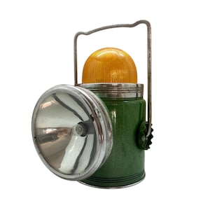Puede incluir: Linterna verde y plateada vintage con parte superior amarilla y asa plateada. La linterna tiene una lente grande y redonda y un cuerpo verde texturizado. Una pieza clásica y funcional.