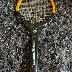 May include: A vintage wooden tennis racket with a black handle and a black and white logo that says "Pro-Tec 55". The racket has a wooden frame and a black stringed head.