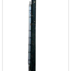 May include: A vintage thermometer with a white and black scale, measuring in Celsius, is displayed next to a dark green cylindrical case. The thermometer has a silver metal tip and a small loop at the top. The case shows signs of wear.