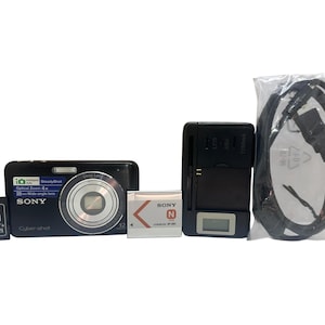 Może przedstawiać: Czarny aparat cyfrowy Sony Cyber-shot z srebrnym obiektywem, baterią, ładowarką, adapterem kart pamięci i kablem USB. Na aparacie znajduje się napis "Sony Cyber-shot" i "Optical Zoom 4x".