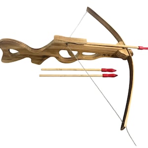 Puede incluir: Una ballesta de juguete de madera con tres flechas. La ballesta tiene un acabado marrón claro con un arco curvado y una cuerda. Las flechas son de madera con puntas rojas. El juguete está diseñado para niños.
