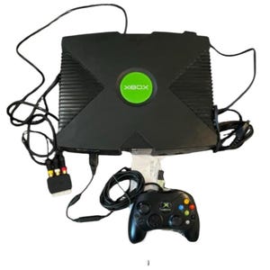 Peut inclure: Console Xbox noire avec un logo vert, une manette noire et divers câbles. La console a un design distinctif avec un logo X proéminent. La manette comporte des boutons colorés et des joysticks.