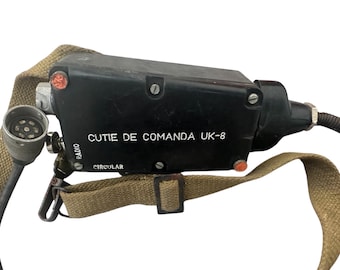 May include: A black radio control box with the text "CUTIE DE COMANDA UK-8" and "CIRCULAR" printed on it. It has a khaki-colored strap and a connector cable. The box has a few red buttons and a silver connector.