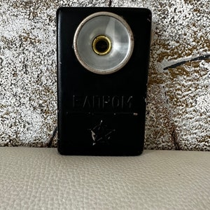 Puede incluir: Un silbato de metal negro con una boquilla de metal plateado y la palabra "FANTOM" en relieve en la parte delantera.