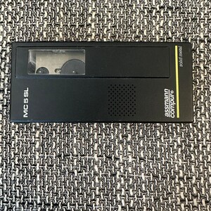 May include: A black cassette recorder with a clear window showing the cassette tape. The recorder has a small speaker and the text "MC 55 SL" and "assmann compur" printed on it.