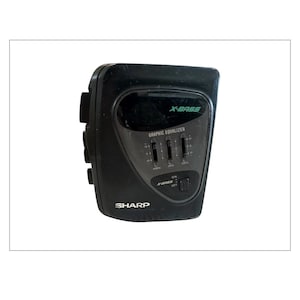 May include: A black Sharp X-BASS graphic equaliser with sliders and an on/off switch. The text "X-BASS" is in green, and the brand name "SHARP" is printed at the bottom.