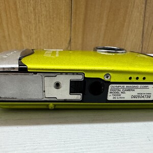 May include: A yellow Olympus digital camera with a silver top and black lens. The camera has a model number of 790SW and a serial number of D92504739.