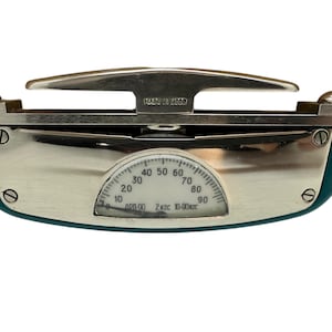 Könnte beinhalten: Vintage Waage in Teal und Silber mit einer gebogenen Anzeige, die Zahlen von 10 bis 90 anzeigt. Die Waage hat einen silbernen Griff und den Text "MADE IN USSR".