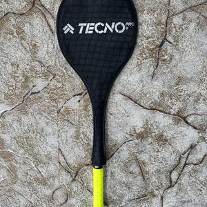 May include: Black and yellow badminton racket with the text "TECNO PRO" on the head of the racket.