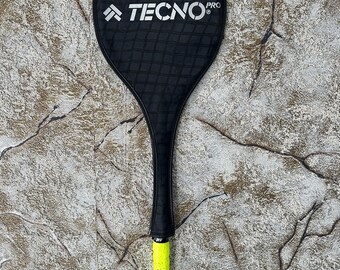 以下が含まれることがあります： ラケットヘッドに「TECNO PRO」の文字が書かれた、黒と黄色のバドミントンラケット。