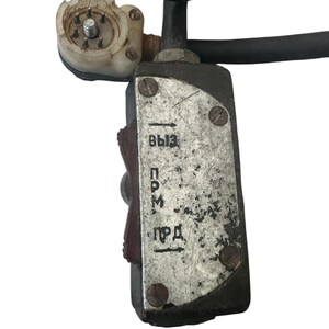 Puede incluir: Primer plano de un componente eléctrico con un cable negro y una caja metálica rectangular. La caja tiene el texto cirílico "ВЫЗ", "ПРМ" y "ПРД" impreso. Se adjunta un pequeño conector blanquecino.