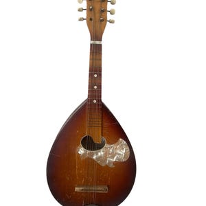 May include: A vintage mandolin with a pear-shaped body and a wooden neck. The instrument has a sunburst finish, transitioning from dark brown to light brown. It features a decorative pearlescent pickguard and tuning pegs.
