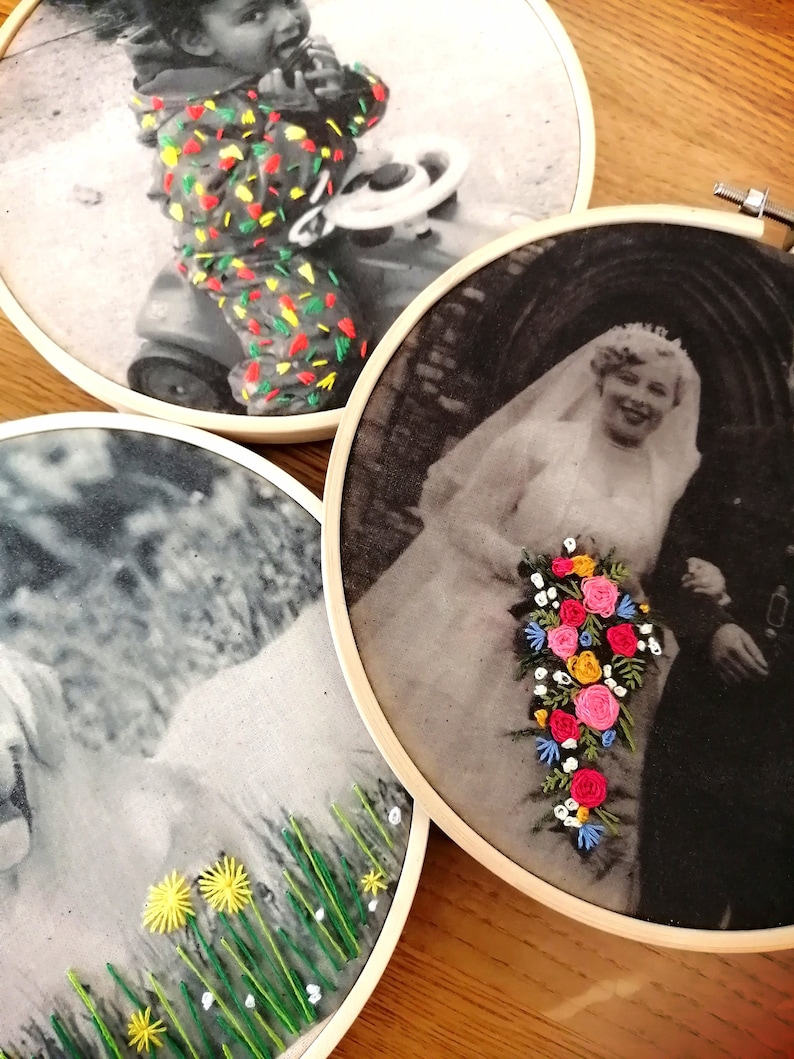 May include: Three embroidered hoop art pieces featuring black and white photos. The first hoop shows a young child in a colorful outfit riding a toy car. The second hoop shows a bride and groom in a black and white wedding photo with a bouquet of embroidered flowers. The third hoop shows a black and white photo of a person with embroidered green grass and yellow flowers.