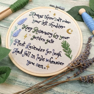 May include: Embroidered hoop with a white background and a handwritten quote about herbs and love. The quote reads: "Always throw salt over your left shoulder. Keep Rosemary by your garden gate. Mint Lavender for luck. And fall in love whenever you can."