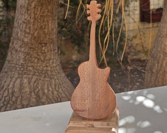May include: A wooden guitar sculpture with a natural wood finish. The guitar is mounted on a wooden base.