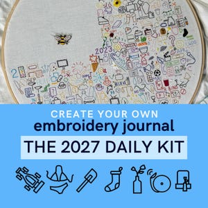 May include: A circular wooden embroidery hoop containing white fabric with a dense collection of colorful, small embroidered icons and symbols. A small bee pin is attached to the fabric. The design includes various shapes, text, and dates.