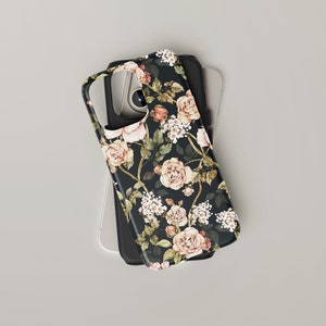 May include: A black phone case with a floral pattern featuring pink and white roses and green leaves on a black background.