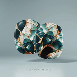 Op de afbeelding: Twee abstracte, organisch gevormde objecten met een geometrisch patroon in goud, wit en teal. De objecten zweven in de lucht tegen een lichtblauwe achtergrond.