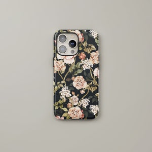 May include: A black phone case with a floral pattern featuring pink and white roses, green leaves, and white flowers. The case has a cutout for the phone's camera.