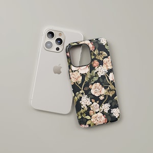 May include: A white iPhone with a floral phone case. The case has a black background with pink and white flowers.