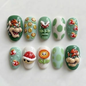 May include: A set of ten press-on nails featuring 3D designs inspired by Super Mario characters and items. The collection includes Bowser, gold coins, fire flowers, piranha plants, red shells, Cheep Cheep fish, and green and white polka dot patterns.